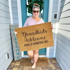 a woman holding a sign that says grandkids welcome