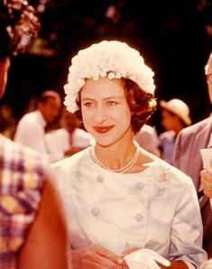 an old photo of a woman wearing a flowered hat and pearls on her head