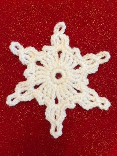 a crocheted snowflake on a red surface