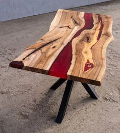 a table made out of wood with red and black paint on the top, sitting in front of a building