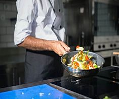 a chef is cooking vegetables in a wok