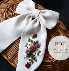 a bow tie with flowers on it is sitting in a basket next to a piece of cloth