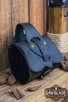 a black leather bag sitting on top of a wooden table