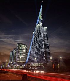 a very tall building sitting in the middle of a city at night with lights shining on it