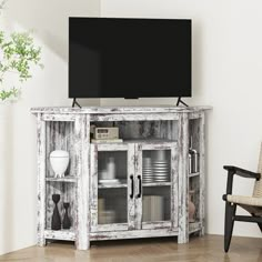 an old white cabinet with glass doors in the corner and a black television on top