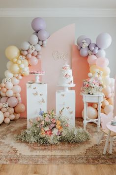 a table topped with lots of balloons next to a cake and vase filled with flowers