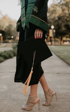 a woman walking down a sidewalk with her graduation cap and gown hanging off the side