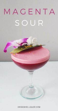 a pink drink in a wine glass with flowers on top and the words magenta sour above it