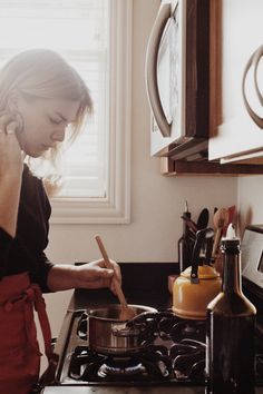 a woman in an apron is cooking on the stove