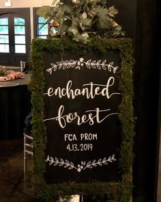 a chalkboard sign with greenery on it