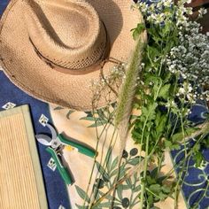 a straw hat sitting on top of a blue and white blanket next to flowers, pliers and scissors