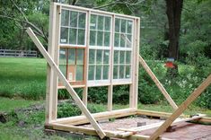 a wooden structure sitting in the middle of a yard with windows on it's sides