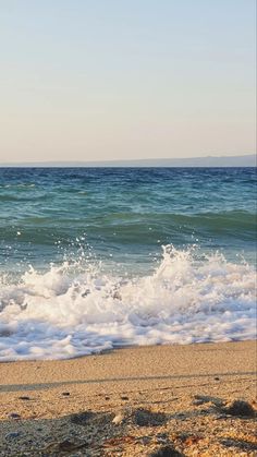 a person standing on the beach with a surfboard in their hand and looking at the ocean