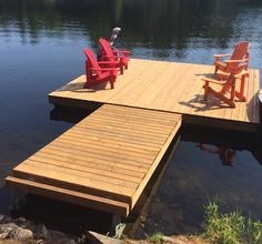 two red chairs sitting on top of a wooden dock