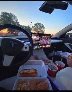 a person sitting in the driver's seat of a car while eating food and watching tv