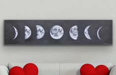 a couch with two pillows and a painting on the wall above it that has five phases of the moon