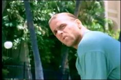 a man standing in front of a tennis ball and racket with his head turned to the side