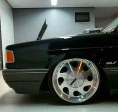 a black car with chrome rims parked in a garage next to a white wall