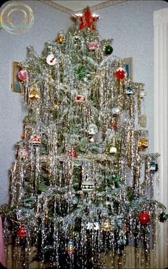 a christmas tree is decorated with ornaments and tinsels in the shape of an xmas tree