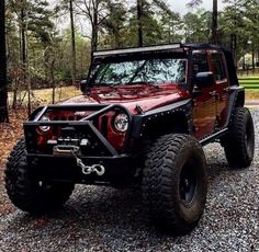 a red jeep is parked in the gravel