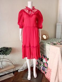 Cute True Vintage prairie dress from the early 1980s. Structured semi sheer light fabric in a beautiful tone of coral red. High neck with lace and satin tie band. More lace and satin details on the bib. Half long puff sleeves, elasticated cuffs. Elasticated waist. Wide skirt with ruffle hem. Lined skirt. Made in France! BRAND: No brand label anymore ERA: 1980s COLOR: Coral red  Fabric: 67% polyester, 33% cotton; lining 100% polyamide SIZE: Vintage size FR44, runs smaller and  fits best size S-M Vintage Prairie Dress, Wide Skirt, Brand Label, Prairie Dress, Coral Red, Red High, Color Coral, Lined Skirt, Long Puff Sleeves