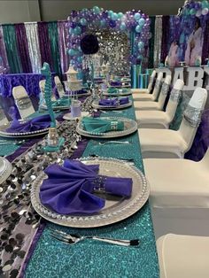 the table is set with purple and blue decorations, silverware, and napkins