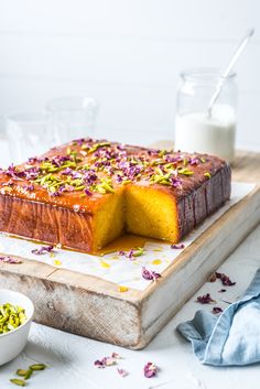 a cake on a cutting board with a slice cut out and flowers scattered around it