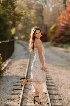 a woman standing on train tracks with her legs in the air and smiling at the camera