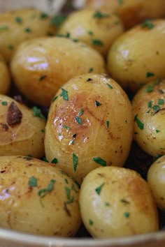 a bowl filled with potatoes covered in seasoning and sprinkled with parsley