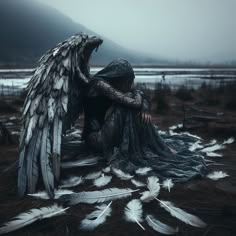 a woman sitting on the ground with wings in her hands, surrounded by white feathers