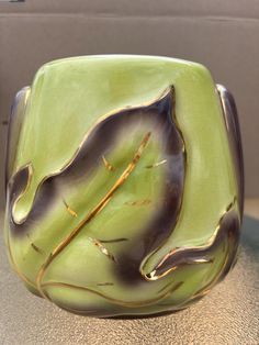 a green vase sitting on top of a table next to a black and gold object