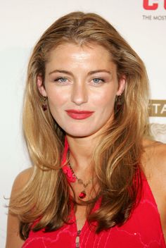 a woman with long blonde hair and blue eyes wearing a red dress at an event