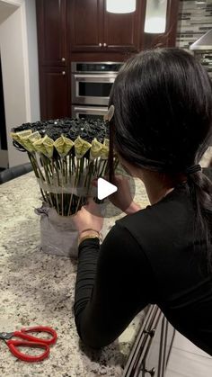 a woman sitting at a kitchen counter with scissors