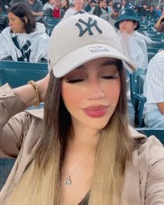 a woman with long hair wearing a new york yankees hat