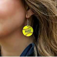 a close up of a person wearing a pair of earrings with softball designs on them