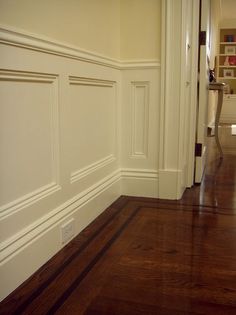 an empty room with hard wood floors and white paint on the walls, in front of a bookcase