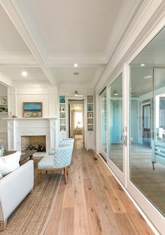 a living room with wood floors and white furniture in front of glass doors that lead to an outdoor patio