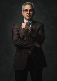 a man in a suit and tie posing for a photo with his arms folded up