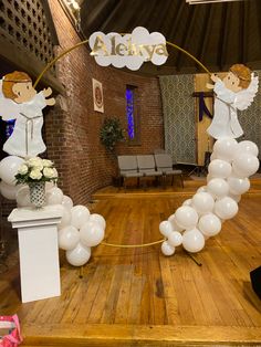 balloons are arranged in the shape of an arch with angels on it, along with flowers and candles