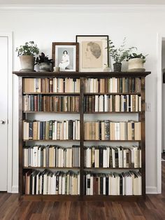 a bookshelf filled with lots of books on top of wooden floors next to a doorway