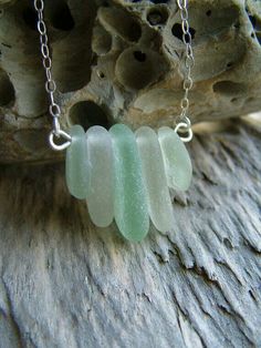 three sea glass necklaces sitting on top of a piece of wood