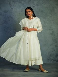 Chanderi kurta in Off White with mirror work on yoke and sleeves. This Front yoke gathered kurta set is paired with a chanderi dupatta with mirror work on borders and comes along with cotton flared palazos highlighted with mirrors.Perfect festive dressing for a glittery evening. Color: Off White Fabric: Kurta- Chanderi Dupatta - Chanderi Palazzo - Cotton Lining - Cotton Note: Available in other colors The product will be delivered within 2-4 weeks of order placed Wash Care - Dry clean only Hand Onam Ideas, Summer Outfits 2020, Cotton Tops Designs, Kurta Set For Women, White Kurta, Sustainable Clothing Brands, Cotton Kurti Designs, Cotton Kurti, Indian Fashion Designers