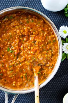 a large pot filled with lots of food on top of a blue table next to flowers