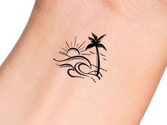 a woman's arm with a palm tree and sun tattoo on the left side