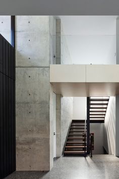 the stairs lead up to the second floor in this modern house with concrete walls and steel railings