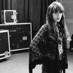 a black and white photo of a woman with long hair standing in front of some suitcases