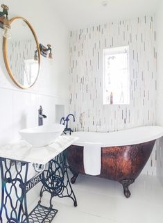 an old fashioned bathtub in a bathroom with two sinks and a mirror on the wall