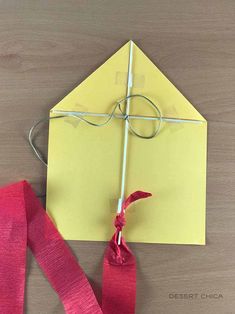 a piece of yellow paper with a red ribbon tied to it