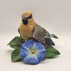 a figurine of a bird sitting on top of a blue and white flower