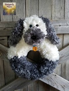 a gray and white dog stuffed animal hanging on a wooden door with an orange tag